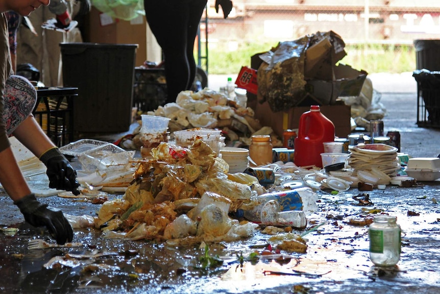 Piles of waste from a day at a Darwin market laid out on the floor, including food scraps and bin juice.