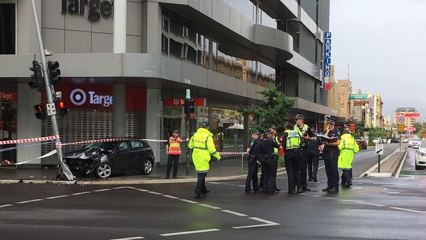 Police stand in the middle of the road, crashed car in the background