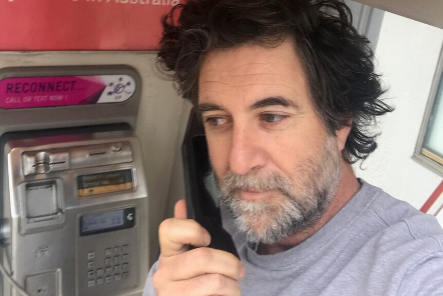 A selfie of a man answering a payphone