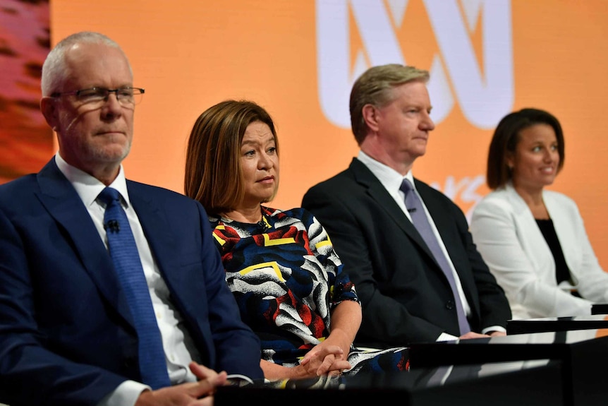 Four people sitting at the front of a studio.