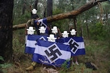 Seven members of the neo-Nazi group Antipodean Resistance holding flags with swastikas in a Victorian forest.