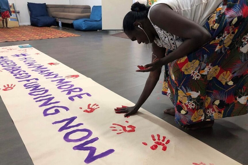 a woman making a hand print on a banner