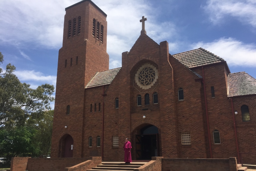 Bishop Donald Kirk stands on the front steps of the red-brick Griffith Anglican Cathedral.