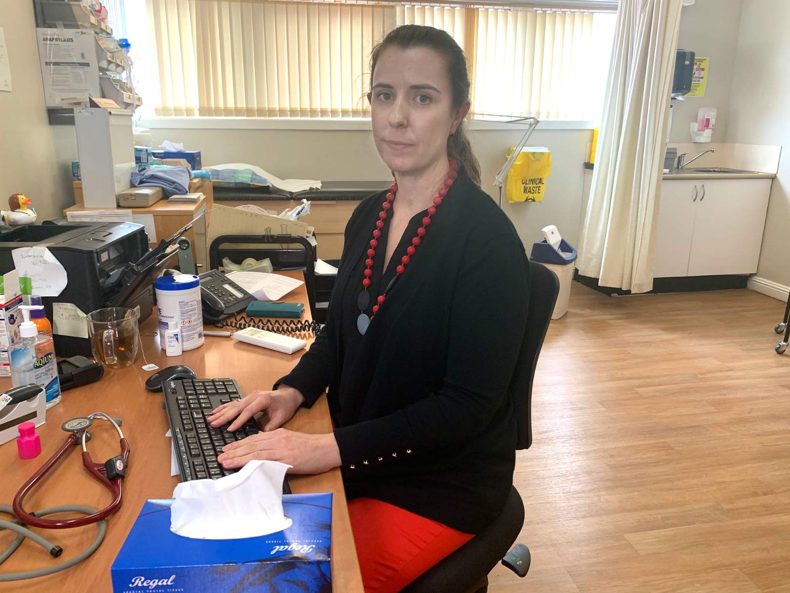 a woman sitting at a computer desk in a doctor's office