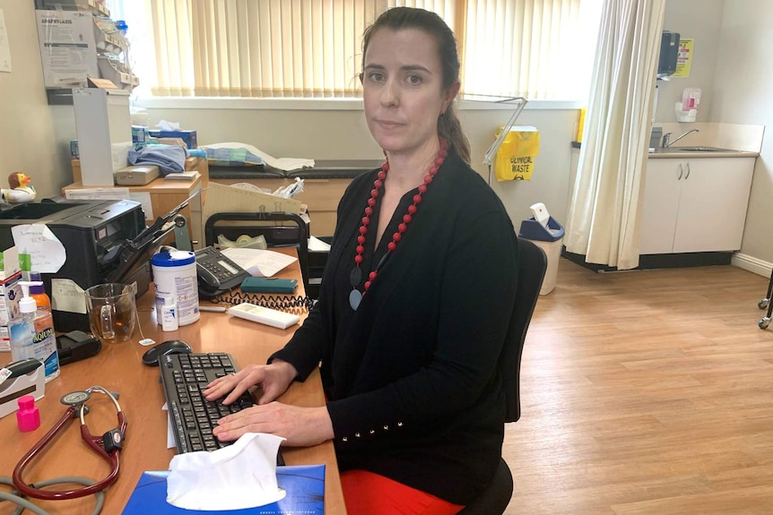 a woman sitting at a computer desk in a doctor's office