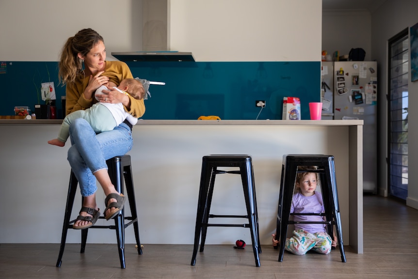 Kara breast feeds her youngest, Lachy,  in the kitchen. 