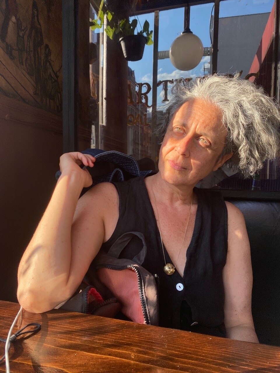 A middle-aged woman sits in a cafe and stares off into the distance.