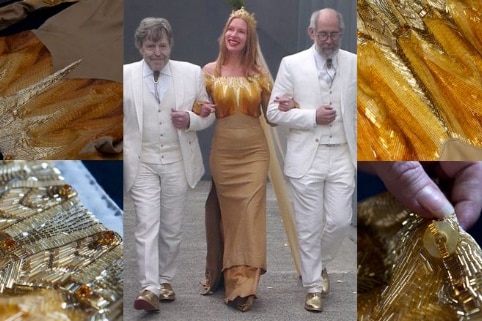 A woman in a gold beaded wedding dress has two men on her arms in white suits.