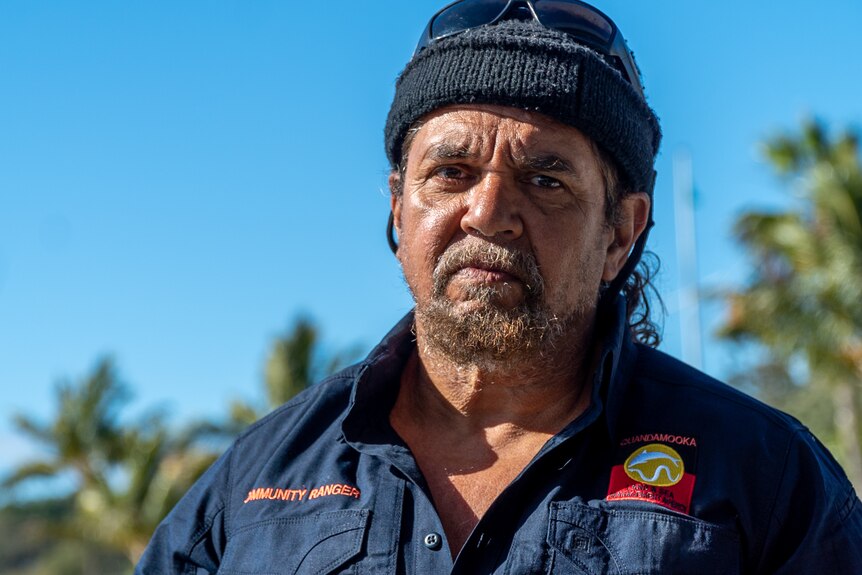 An Aboriginal man in a blue shirt and beanie looking at the camera