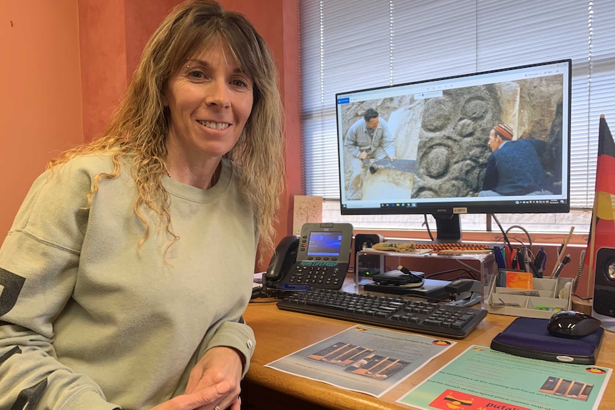 Sharnie Read from the Tasmanian Aboriginal Centre's heritage department sits in front of a computer monitor.