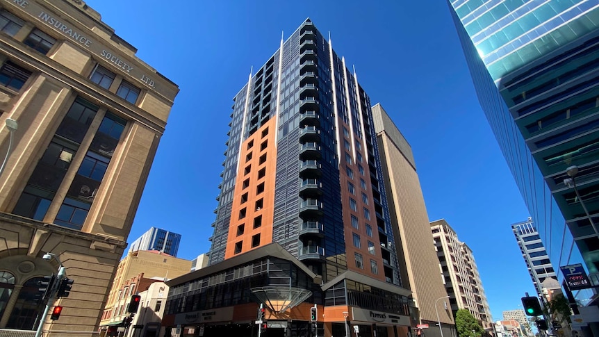 A tall building on a city street with cars driving past