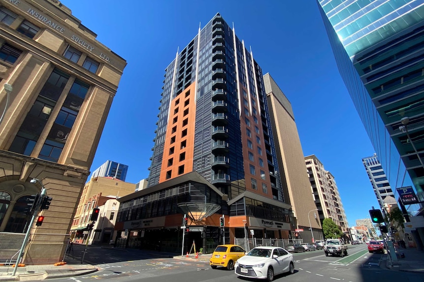 A tall building on a city street with cars driving past