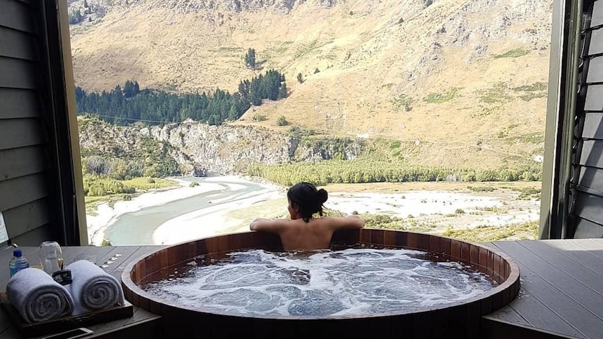 Priya in a large hot tub overlooking mountain scenery, in a story about divorce stigma.