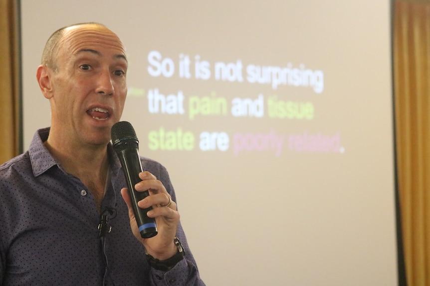 Professor Lorimer Moseley speaks into a microphone.