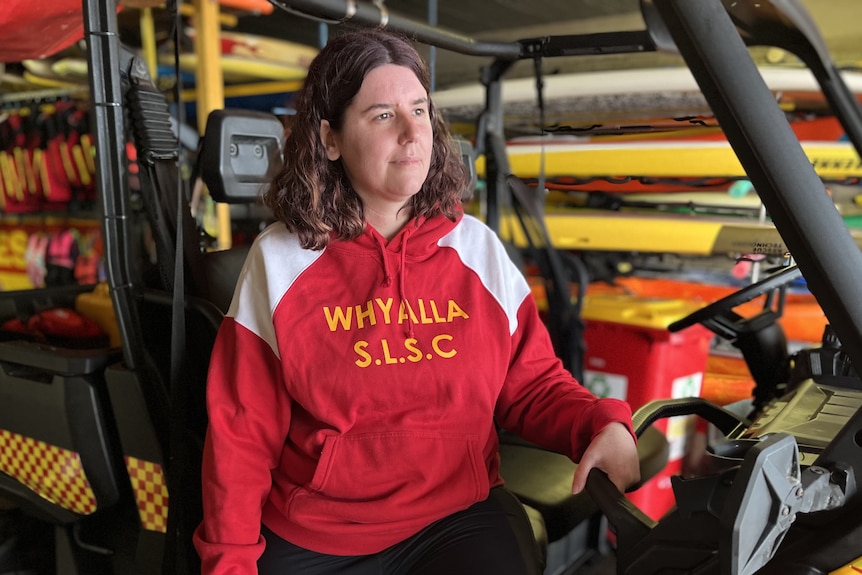 Whyalla Surf Life Saving Club member Rachel Barlow sitting in an ATV with surf life saving equipment in the background. 