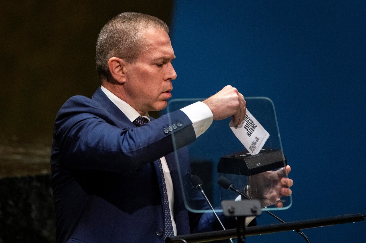 A man in a suit shreds a piece of paper in a shredder