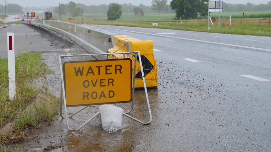 A yellow sign that says: WATER OVER ROAD.