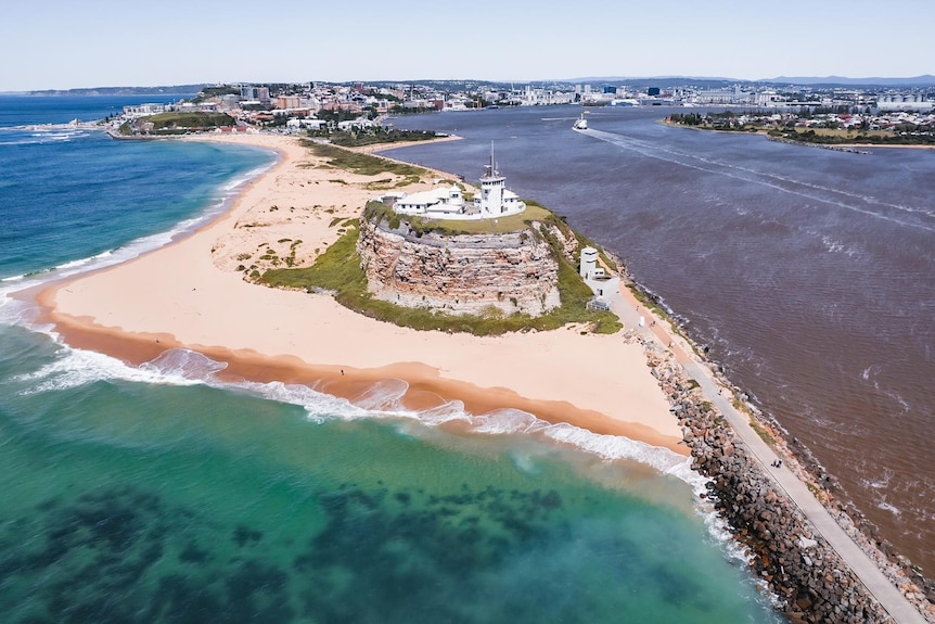 an aerial drone shot of nobbys beach newcastle showing the difference between harbour water and ocean water