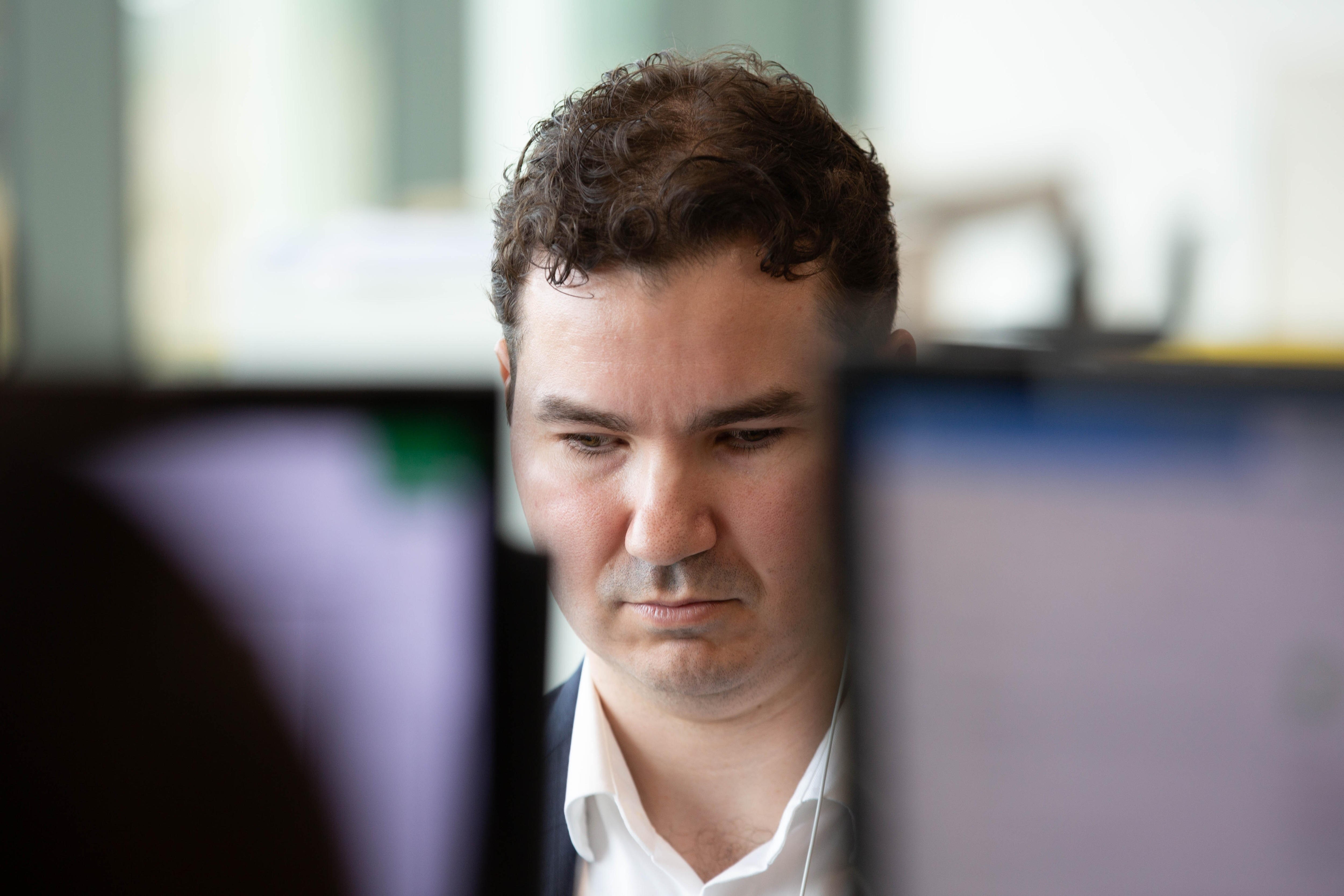 A white man with short hair and a blue suit sitting at a laptop