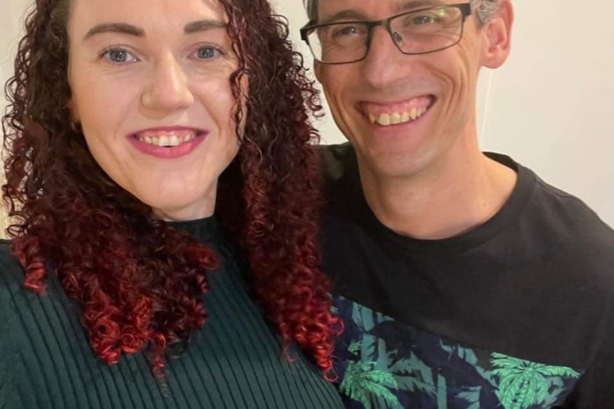 Man and woman happily grin standing close together