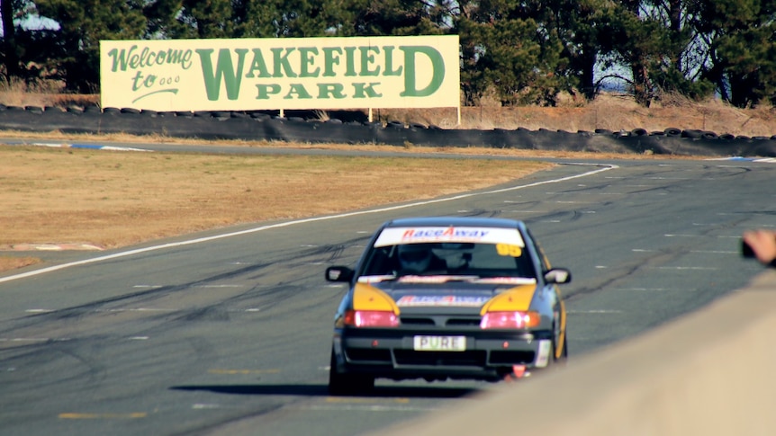 A car drives on a track in front of the Wakeifeld park sign