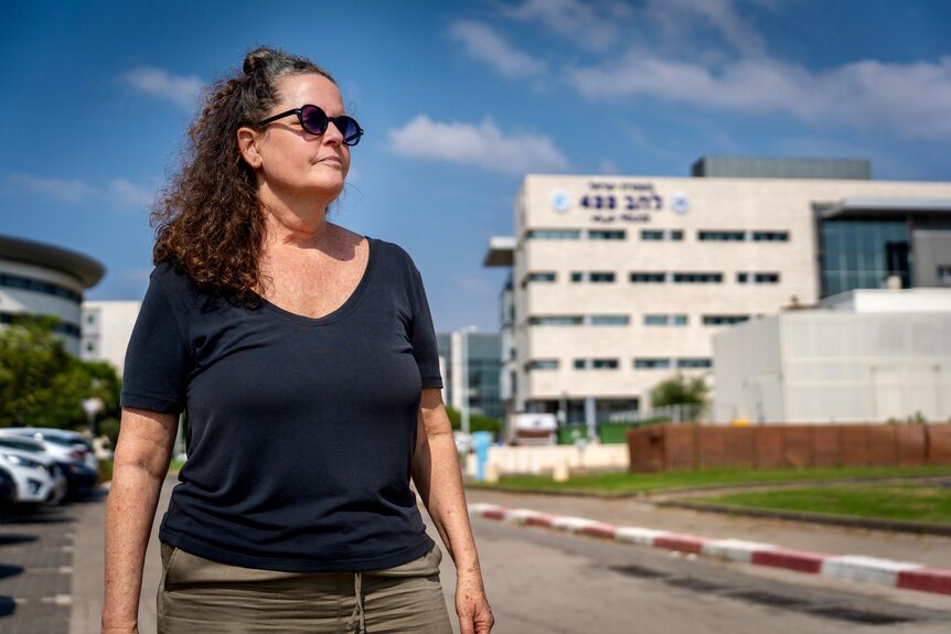Woman in sunglasses stands outside building