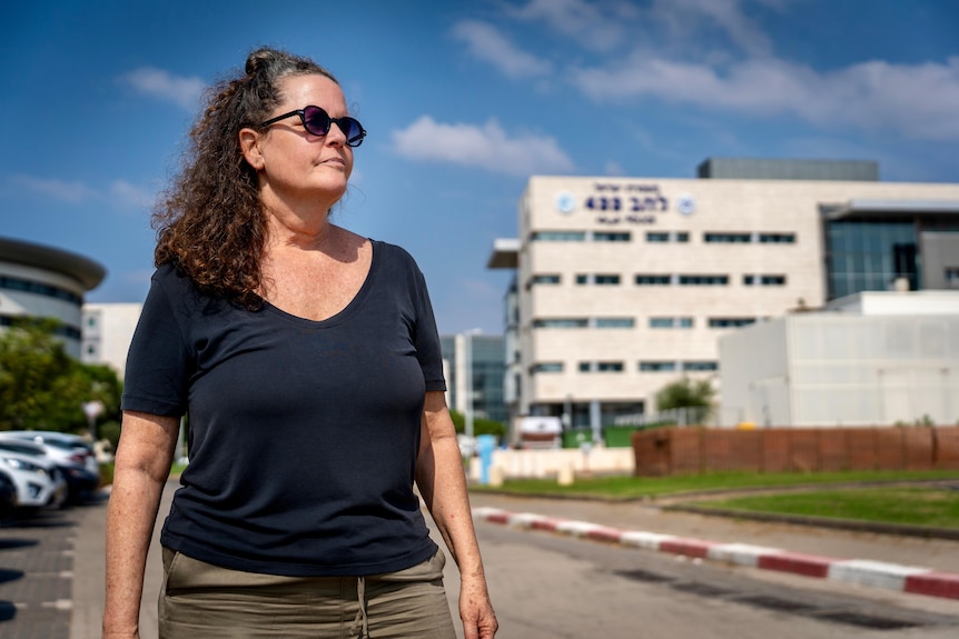 Woman in sunglasses stands outside building