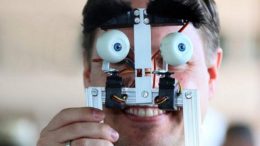 A man holds up a self-made 'face' at the Campus Party Europe electronic entertainment event.