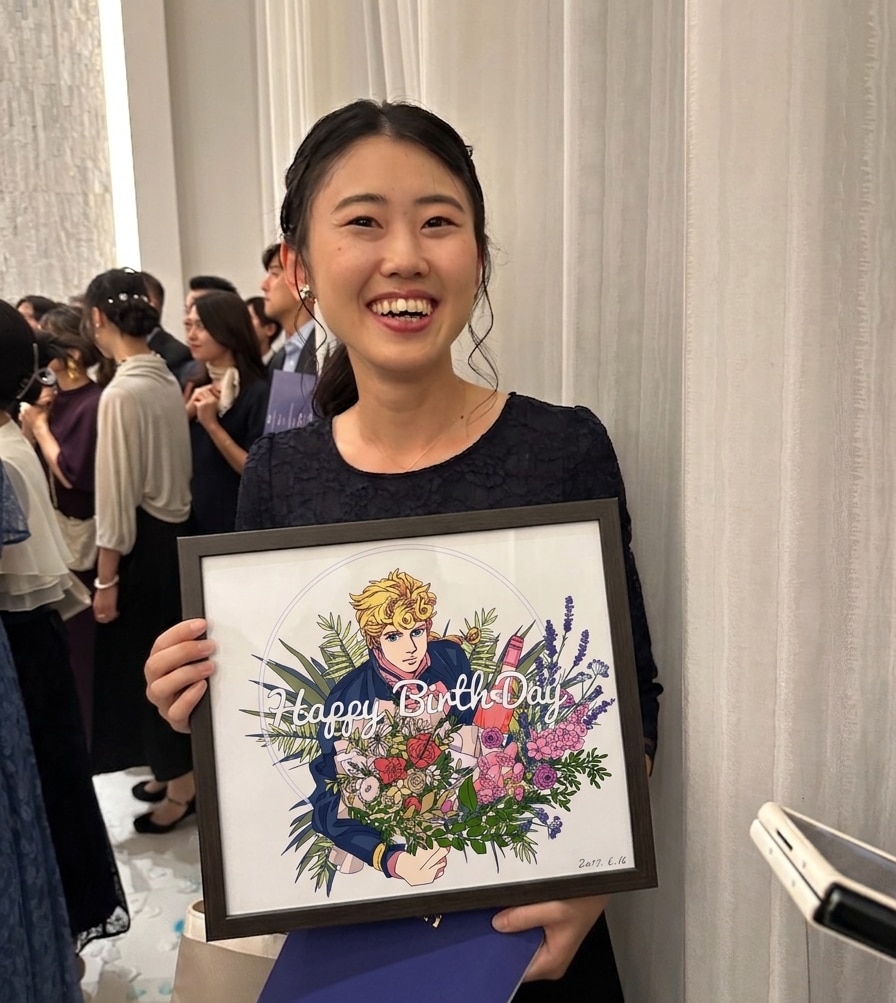 A young woman smiles while holding a picture of an anime character.