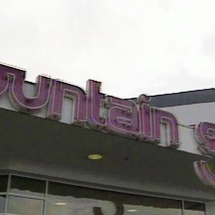 A large unlit neon purple sign above a wide glass entrance doorway: 'fountain gate'.