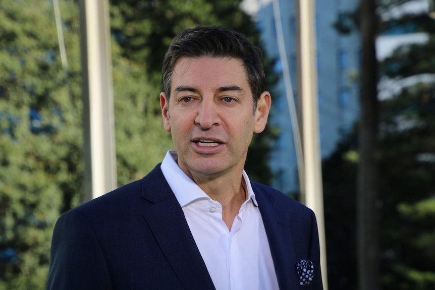 Mid shot of a man wearing a suit, looking past the left of the camera.