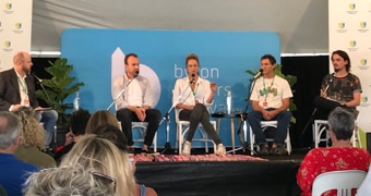 Five people sit on a stage in front of an audience.