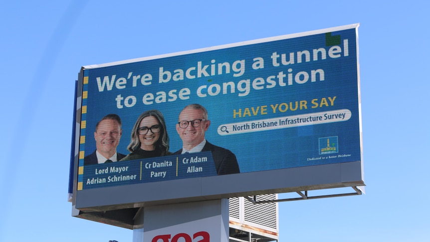 An image of a blue billboard featuring three people and the words 'We're backing a tunnel to ease congestion'.