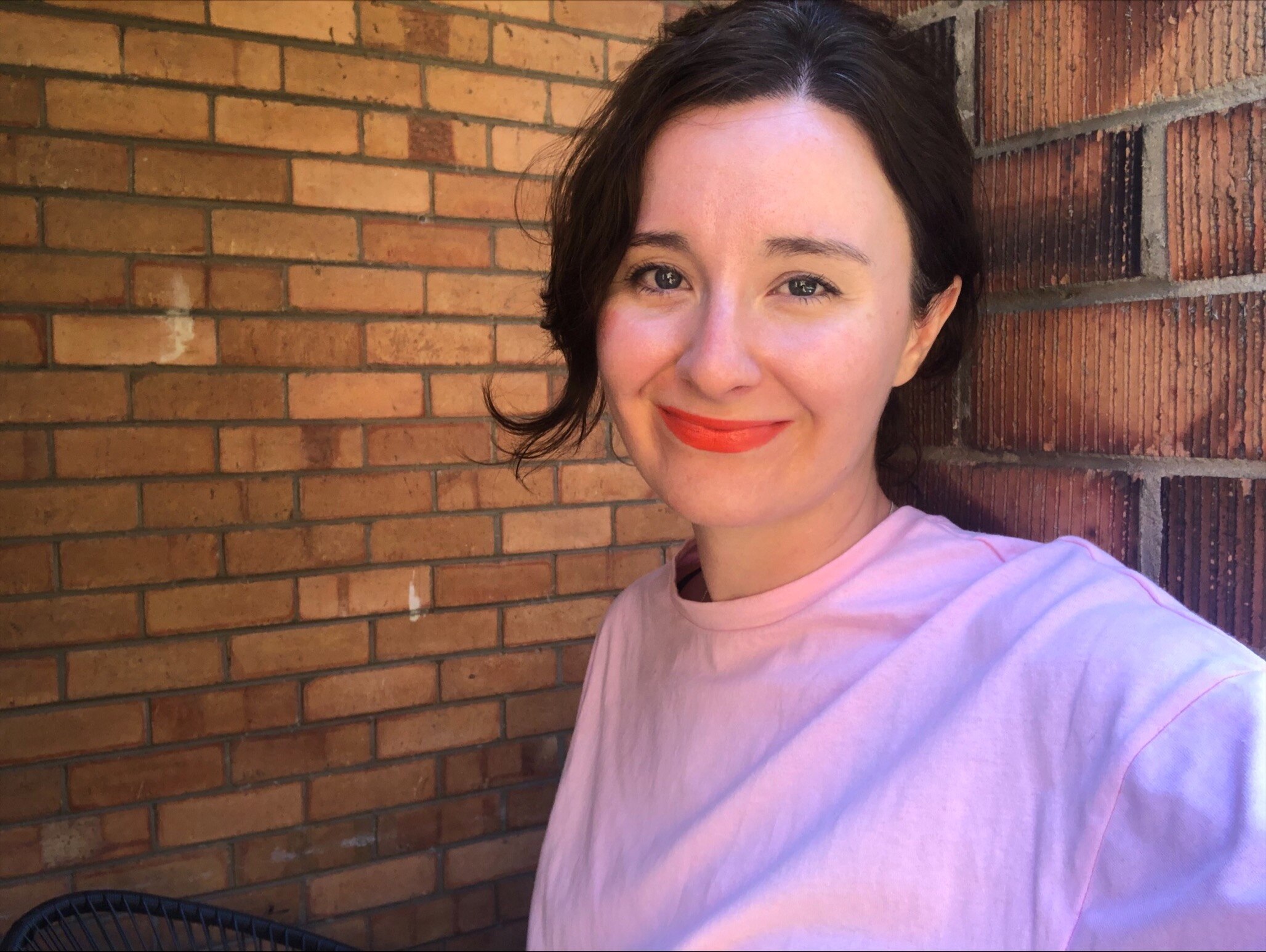 Meg Watson standing against an old brick wall of a Melbourne unit.