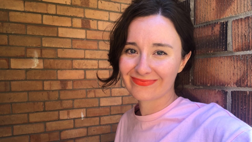 Meg Watson standing against an old brick wall of a Melbourne unit.