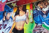 Mural depicting woman in midriff top, shorts and suspenders, surrounded by footballers