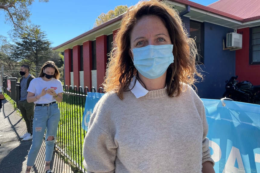 A woman wearing a mask lines up outside a vaccine clinic in Redfern.