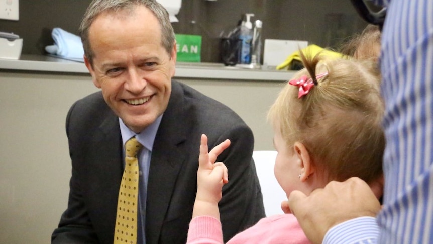 Small girl gives hand gesture to a smiling Bill Shorten