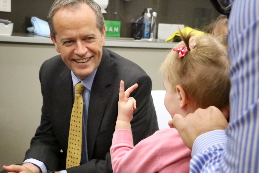 Small girl gives hand gesture to a smiling Bill Shorten