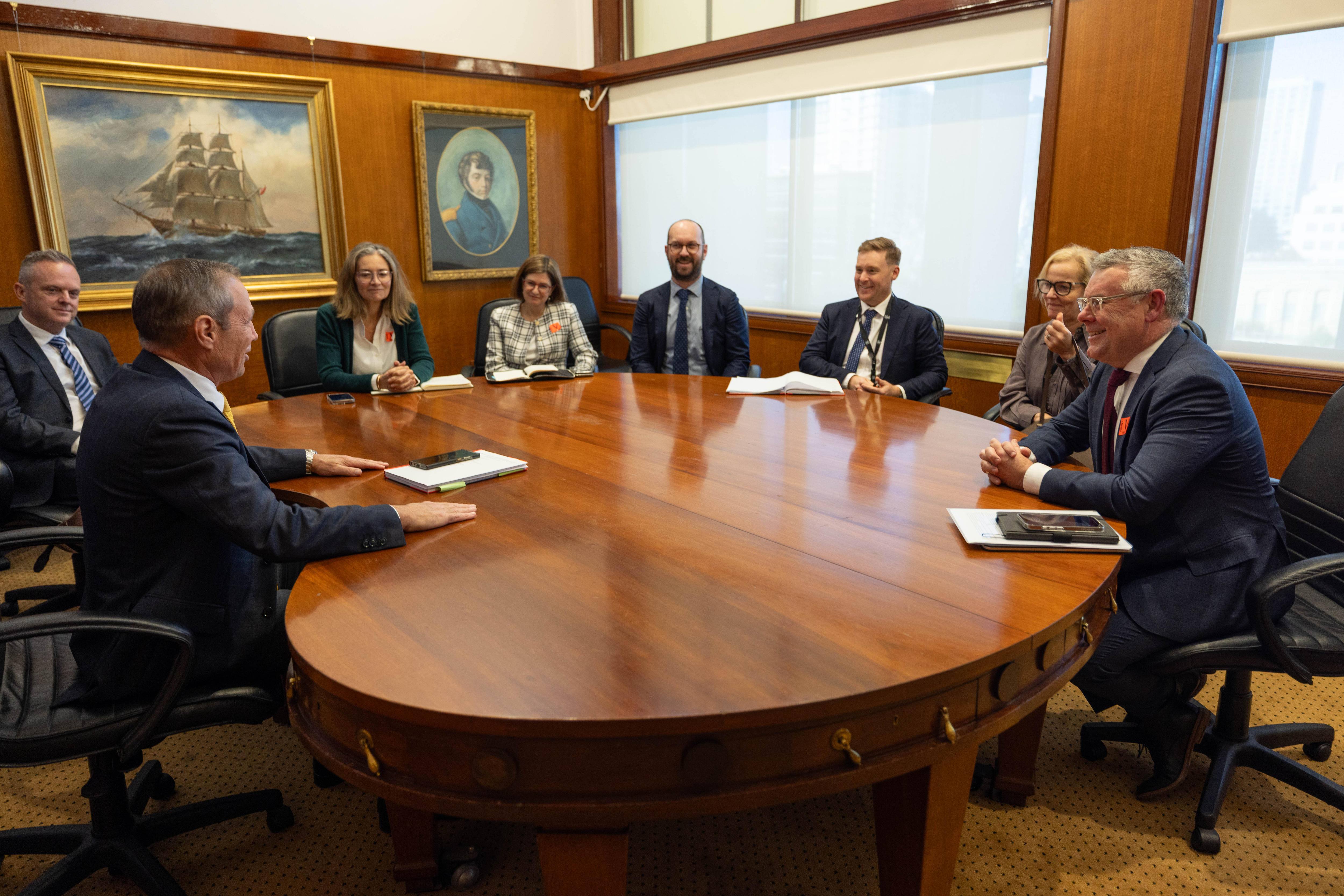 A group of people sitting around a wooden table in a conference room.