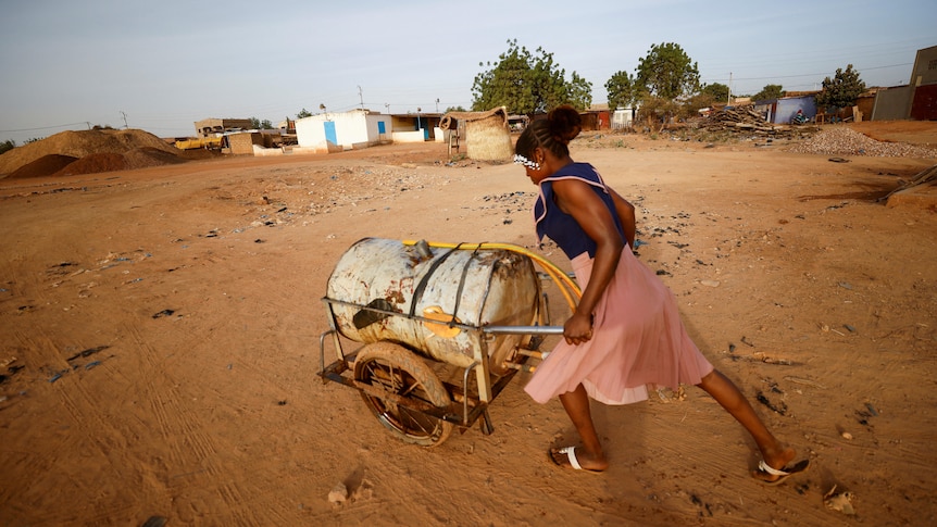 A woman pushes a barrel filled with water on the outskirts of Ouagadougou, Burkina Faso.