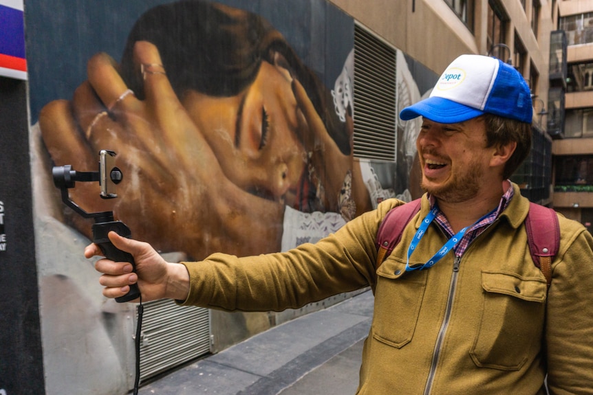 a male tour guide in Melb CBD holding selfie stick