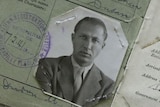 Black and white passport documents of a man in his thirties with tanned skin, piercing eyes, and sandy blond hair in a suit.