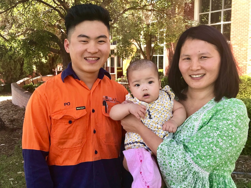 Burmese refugee and TAFE student smiling with his mother and infant sister
