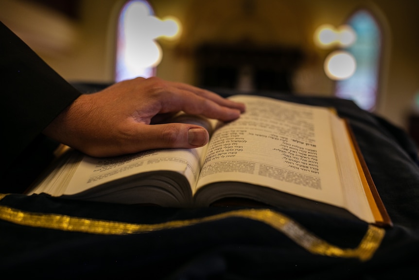 A hand is placed on an open Hebrew Bible.