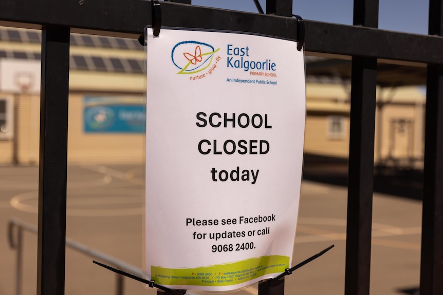 A sign posted at the front of a school saying it is closed.  