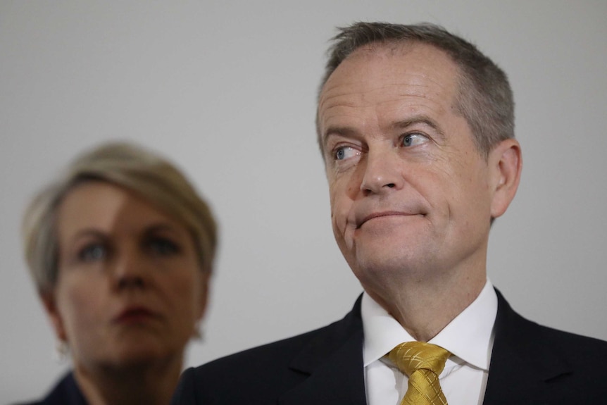 Bill Shorten looks out of the corner of his eye as Tanya Plibersek stands behind him