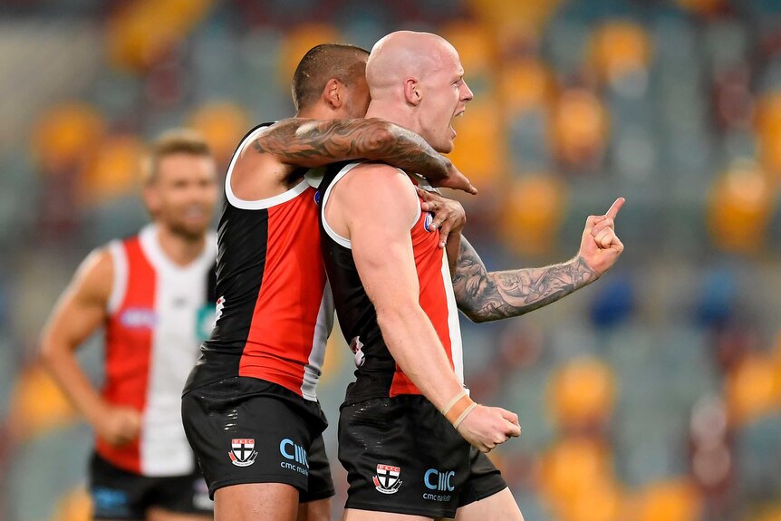 A St Kilda AFL player is hugged around his shoulders by a teammate as they celebrate a goal against Sydney.