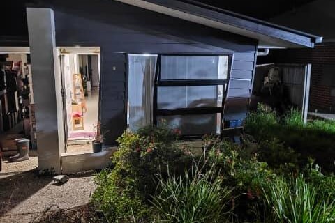 A car resting partially inside a house - which is has smashed intp.