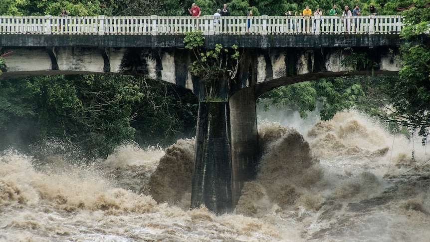 People look over the Wainaku Street bridge as Wailuku River rages below them in Hilo, Hawaii.